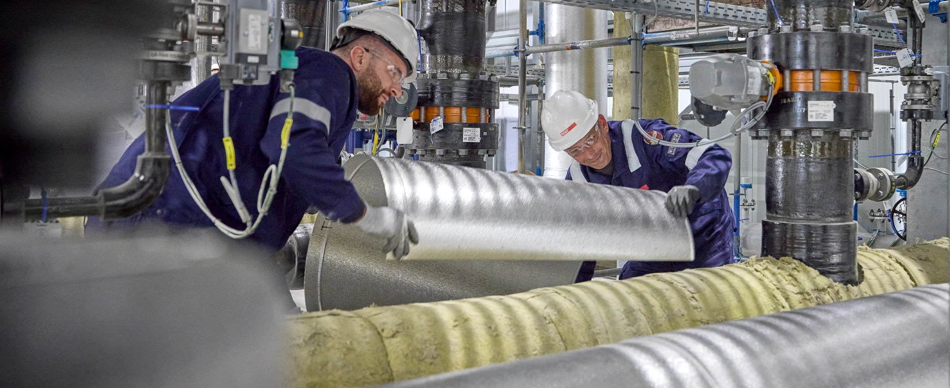 Goed opgeleide vakmensen bekleden installaties met een professionele isolatieconstructie